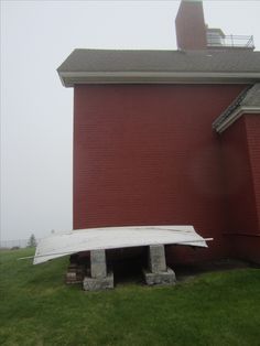 a white surfboard sitting in front of a red brick building on a foggy day