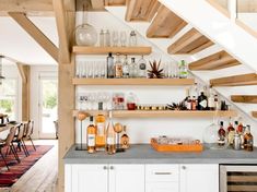 a kitchen with shelves filled with bottles and glasses on top of the counter next to a stair case