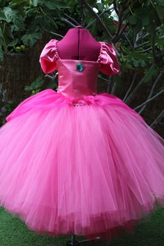 A truly gorgeous shades of Pink ball gown dress inspired by Princess Peach herself. Beautifully handcrafted with hundreds of yards in US  Shades of Pink/ Fuchsia  tulle to make it extra puffy and a satin front bodice with a Blue Jewel Brooch . A beautiful fuchsia organza over-skirt is elegantly draped.  There is also a sewn in pink slip for extra coverage.  The adjustable cap sleeves with ribbon straps tie in the back for the perfect fit! This Tutu dress is amazing for Halloween Parties, Photo s Pink Princess Organza Gown, Pink Tulle Ball Gown For Dress-up, Pink Tulle Ball Gown For Dress-up Events, Pink Tulle Skirt Ball Gown For Dress-up Events, Pink Tulle Gown For Dress-up, Pink Tulle Gown For Dress-up Occasions, Pink Tulle Princess Dress For Fancy Dress Occasions, Pink Princess Dress With Fitted Bodice Ball Gown, Princess Dress With Fitted Bodice In Organza