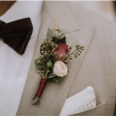 a boutonniere with flowers and greenery on the lapel of a man