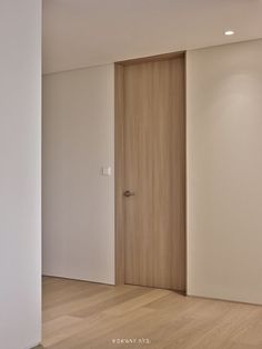 an empty room with white walls and wood floors, two doors open to reveal the bathroom