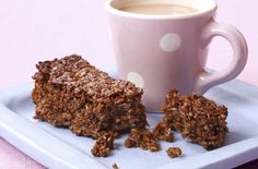 a cup of coffee and some granola bars on a blue plate with a pink background