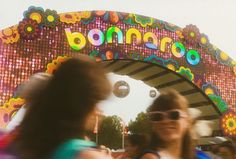 two women are standing in front of a carnival sign with the word bomb on it