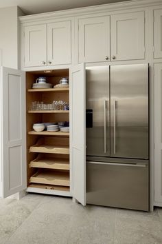 a stainless steel refrigerator freezer sitting inside of a kitchen next to white cupboards