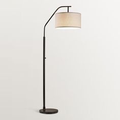 a black floor lamp with a white shade on it's side and a round base