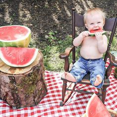 a baby is sitting in a chair with watermelon slices on the picnic table