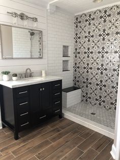 a bathroom with black and white tiles on the walls, wood flooring and a shower stall