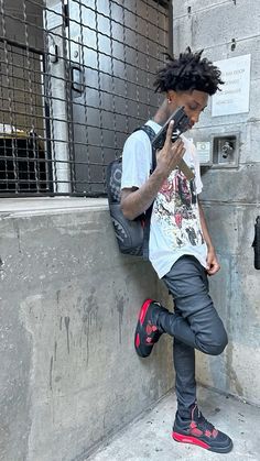 a man leaning against a wall using his cell phone