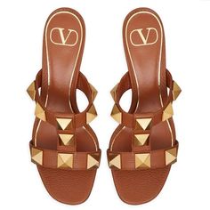 Valentino Garavani Roman Stud Slide Sandals In Moose Print Calfskin Leather. Antique Brass Finish Maxi Studs 18 X 18 Mm / 0.7 X 0.7 In. Leather-Covered Block Heel Heel Height: 60 Mm / 2.4 In. Made In Italy. Valentino Garavani. Color: Saddle Brown. Designer Studded Sandals For Summer, Brown Calf Leather Mules For Summer, Summer Brown Calf Leather Mules, Gold Sandals With Leather Lining For Summer, Designer Calf Leather Sandals With Studded Outsoles, Designer Flat Sandals With Studded Rubber Outsoles, Designer Flat Sandals With Studded Outsoles, Luxury Brown Summer Mules, Luxury Brown Heels For Summer