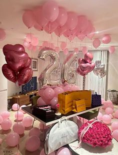 balloons and gifts are on display in the center of a room decorated with pink flowers