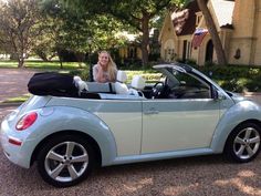 a woman sitting in the back of a blue and white convertible car