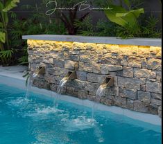 three water jets are running down the side of a swimming pool with rocks on it