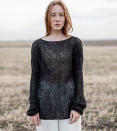 a woman standing in a field wearing a black sweater