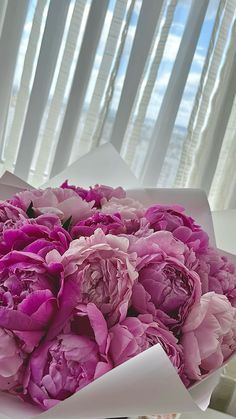 a bouquet of pink peonies in a white box