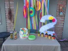 a table topped with a cake next to colorful streamers and paper flowers on top of it