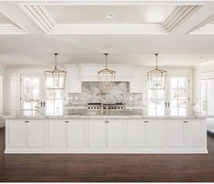 a large kitchen with white cabinets and marble counter tops