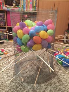 a bunch of balls in a cage on the floor next to some sticks and toys