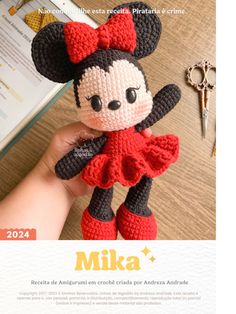 a crocheted minnie mouse doll is shown in front of an open book