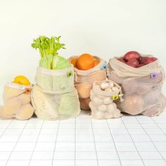 several bags filled with fruits and vegetables sitting on a tiled floor next to a white wall