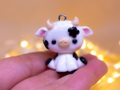 a tiny toy cow is sitting in someone's hand with some lights behind it