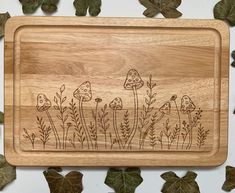 a cutting board with mushrooms on it surrounded by leaves and ivys in the background