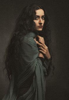 a woman with long black hair wearing a green dress and holding her hands on her chest