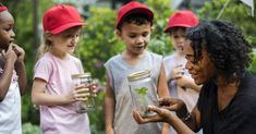 group of children looking at seedlings in jar with woman holding them up to her face