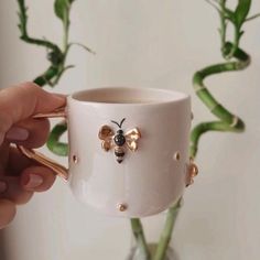 a person holding a coffee cup with a bee on it