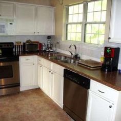 a kitchen with white cabinets and stainless steel appliances, including an oven, dishwasher, sink, microwave, and coffee maker