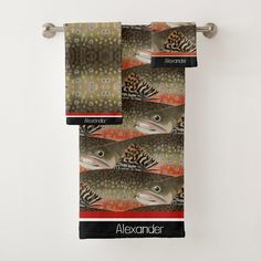 two towels hanging on the wall with fish and leopard print, one has a tag that says alexandder