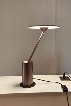 a table lamp sitting on top of a white counter next to a phone charger