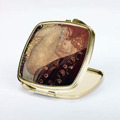 a compact mirror with an image of a man and woman in gold on the front