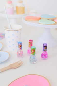 a table topped with plates and cups filled with candy