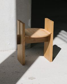 a wooden chair sitting on top of a cement floor next to a wall and door