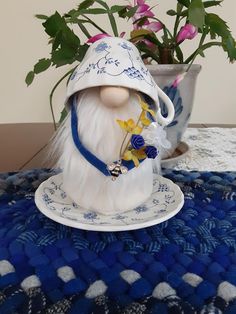 a gnome figurine sitting on top of a blue and white table cloth next to a potted plant