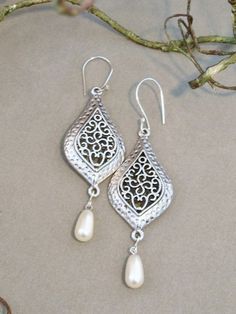 White pearl teardrops hang from intricately detailed, silver plated teardrop shaped components. Ear wires are handcrafted sterling silver wires. Total length 3 1/4 inches long. Sterling Silver Intricate Teardrop Earrings, Sterling Silver Teardrop Earrings With Intricate Design, Ornate Sterling Silver Teardrop Earrings, Sterling Silver Filigree Teardrop Earrings, Silver Filigree Drop Pearl Earrings, Silver Filigree Pearl Drop Earrings, White Metal Teardrop Earrings, Intricate Silver Dangle Pearl Earrings, Silver Drop Chandelier Earrings