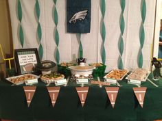 a football themed party with snacks and desserts on a green tableclothed cloth