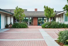 an empty courtyard with plants and flowers in front of the building's entry door