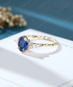 a blue and white diamond ring sitting on top of a card next to some flowers