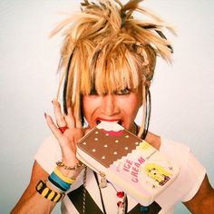 a woman with blond hair eating a piece of cake and making a funny face while holding her hands in front of her mouth