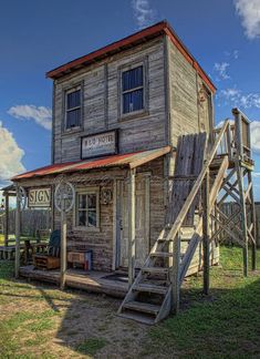 an old wooden building sitting on top of a lush green field next to a life guard tower