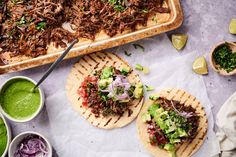 three tacos with meat, avocado and cilantro sauce on the side