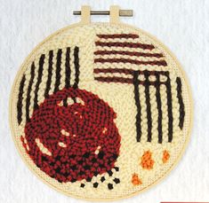 a close up of a embroidery on a white surface with red and black designs in the middle