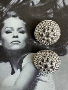 an old photo of a woman with her hair in the wind and two brooches