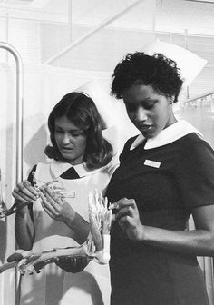 black and white photograph of two nurses looking at something