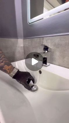 a person with tattoos on their arm is washing his hands in the bathroom sink while wearing gloves