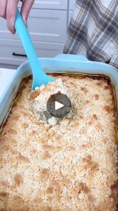 a person holding a blue spatula in a casserole dish with oatmeal