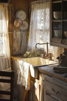 an old fashioned sink in a kitchen with lace curtains and dishes on the window sill