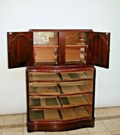 an old wooden cabinet with glass doors on the top and bottom, in front of a white wall