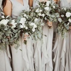 the bridesmaids are holding their bouquets with white flowers and greenery on them